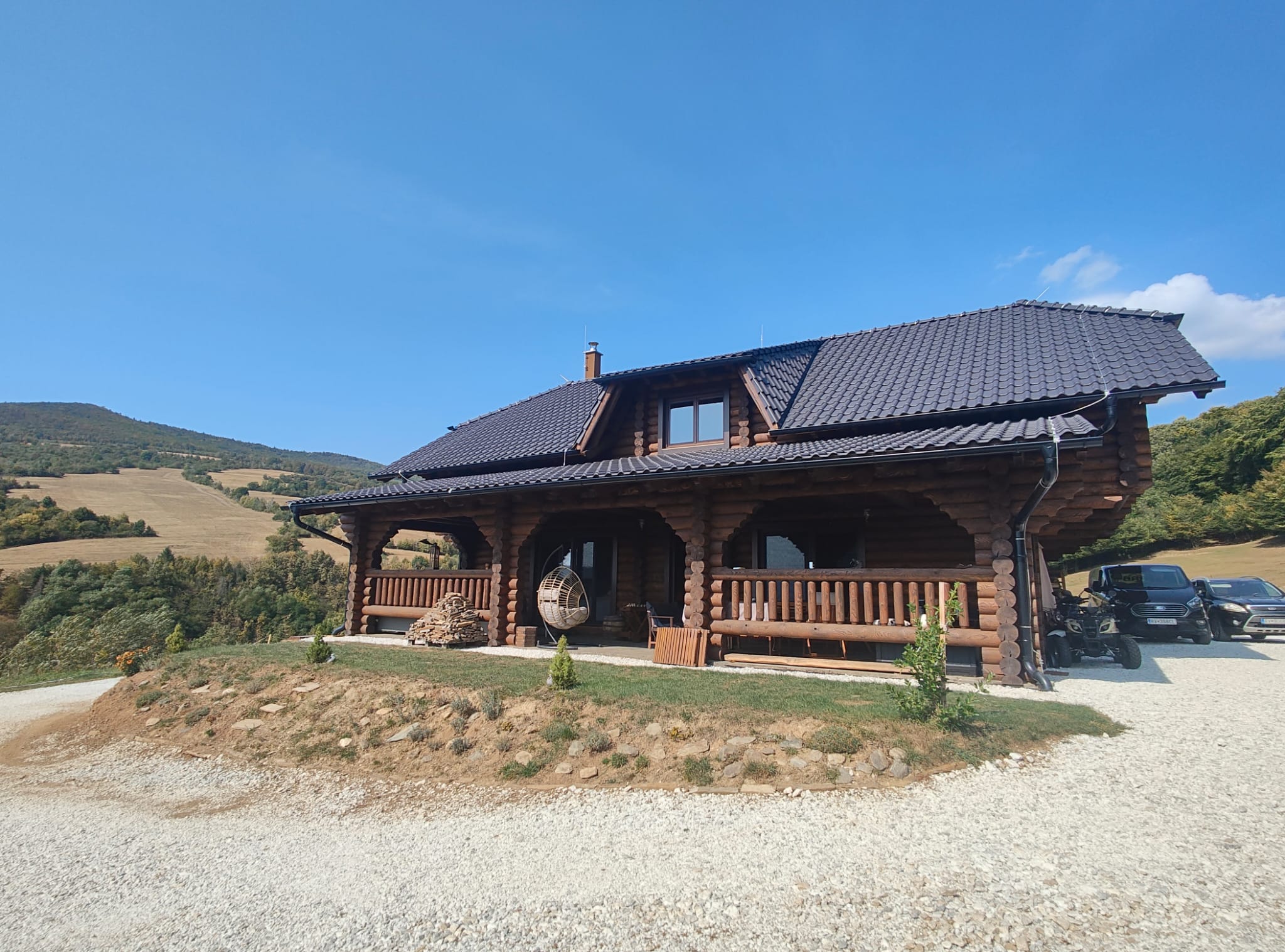 Maison en rondins achevée avec véranda et vue sur les montagnes
